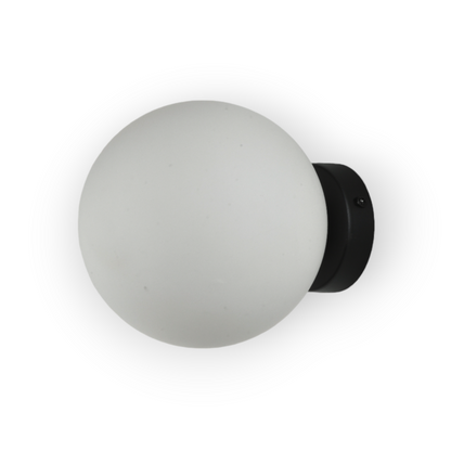 The image displays the Elio Wall Light, a minimalist fixture featuring a base and a frosted glass globe that diffuses light evenly, creating a soft and welcoming ambiance suitable for various interior settings.